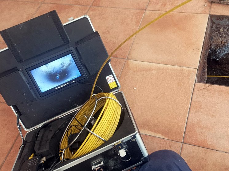 Equipo de inspección con cámara TV junto a una arqueta abierta